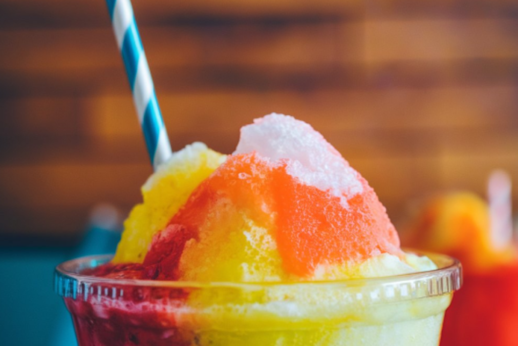 Close-up of a vibrant Icee and Slushie side by side, showcasing the texture and color differences between the two frozen drinks.