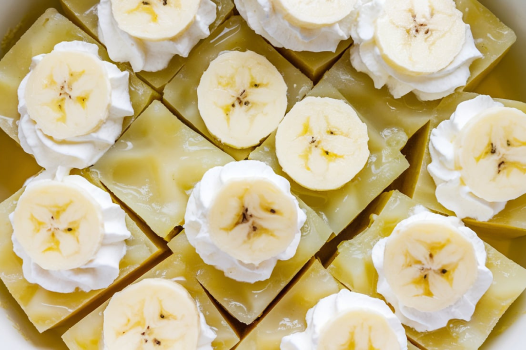 An image showcasing a vibrant yellow bowl of Banana Jell-O, garnished with fresh banana slices and a dollop of whipped cream, served in a white dish.