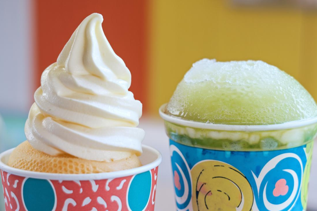 A close-up of an ICEE and a slushie in colorful cups, showing their distinct textures.

