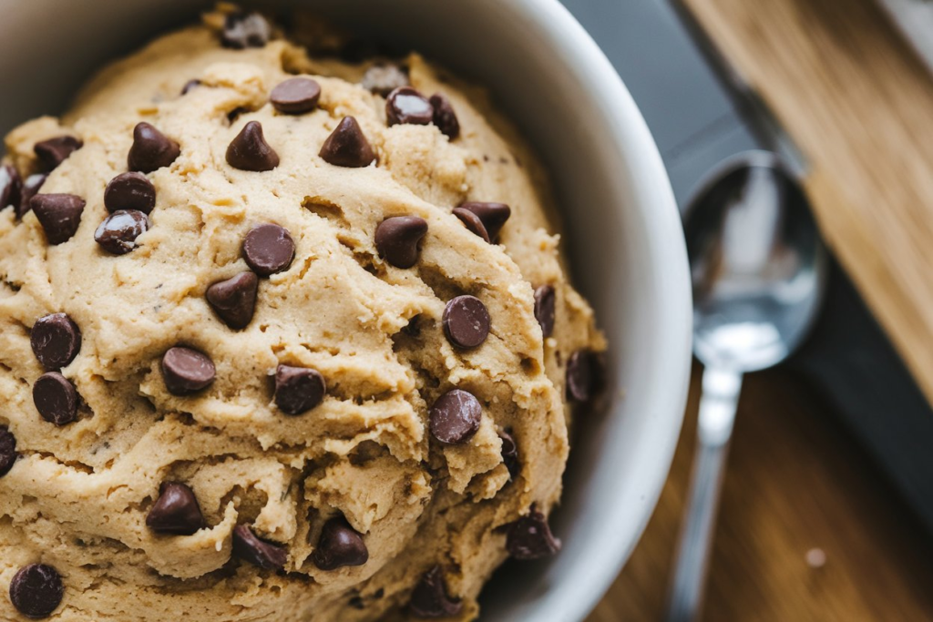 A close-up of edible cookie dough made with heat-treated flour and chocolate chips, safe to eat without baking.