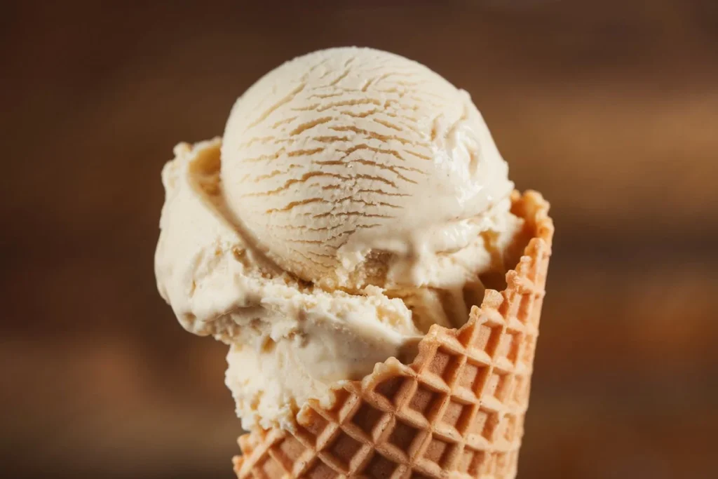 A scoop of homemade vanilla ice cream served in a waffle cone, made using a Cuisinart ice cream maker.

