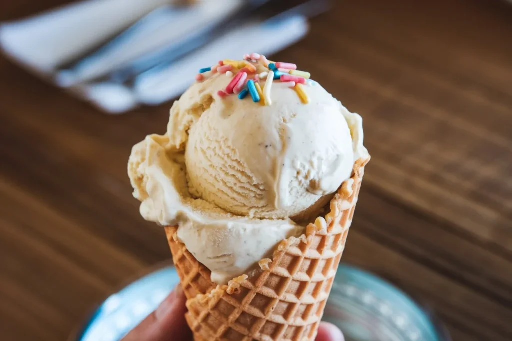 A scoop of homemade vanilla ice cream served in a waffle cone, made using a Cuisinart ice cream maker.

